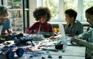 Children working together on computers and robotics in classroom